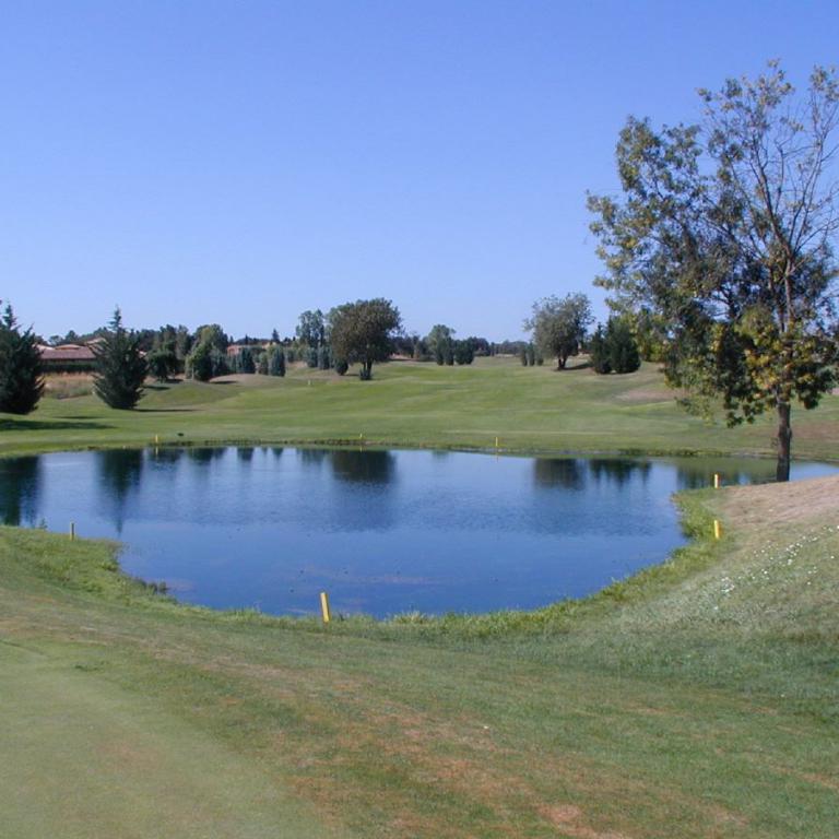Ein Teich inmitten eines Golfplatzes unter blauem Himmel