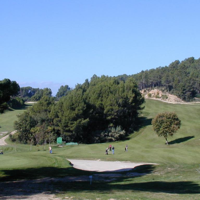 Weitwinkelaufnahme eines Golfplatzes bei klarem Wetter, mit grünen Fairways und Bäumen im Hintergrund.