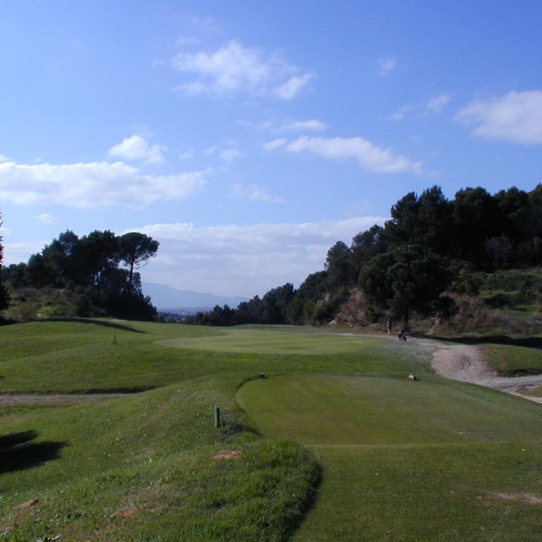 Weitläufiger Blick auf einen Golfplatz bei blauem Himmel mit Wolken