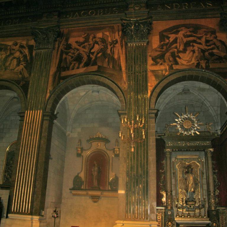 Das Innere einer großen Kirche, erkennbar an hohen Säulen, Rundbögen und Wandmalereien.