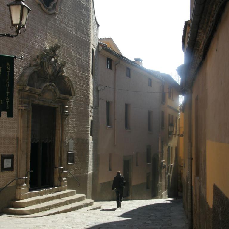 Eine enge, von hohen, historischen Gebäuden gesäumte, gepflasterte Gasse in einer Altstadt.