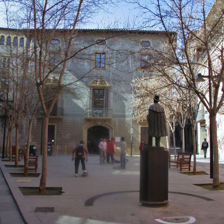 Historischer Innenhof, umgeben von Gebäuden, mit einer Statue im Zentrum.
