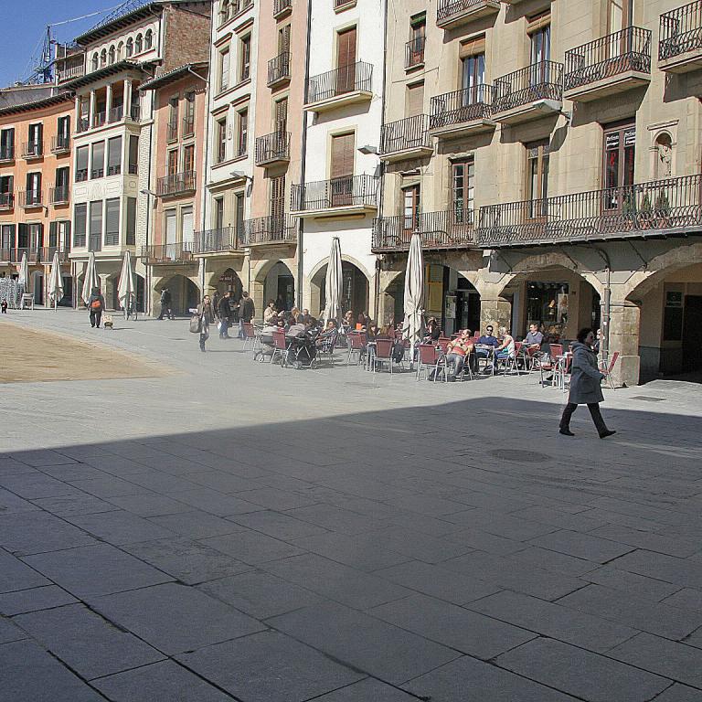 Ein großer, gepflasterter Stadtplatz in einer europäischen Altstadt, umgeben von historischen, mehrstöckigen Gebäuden.