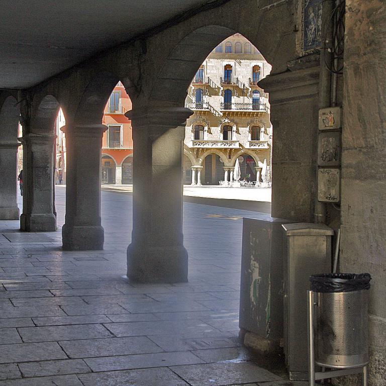 Ein Blick durch eine steinernen Arkade auf historische, farbenreiche Gebäude.