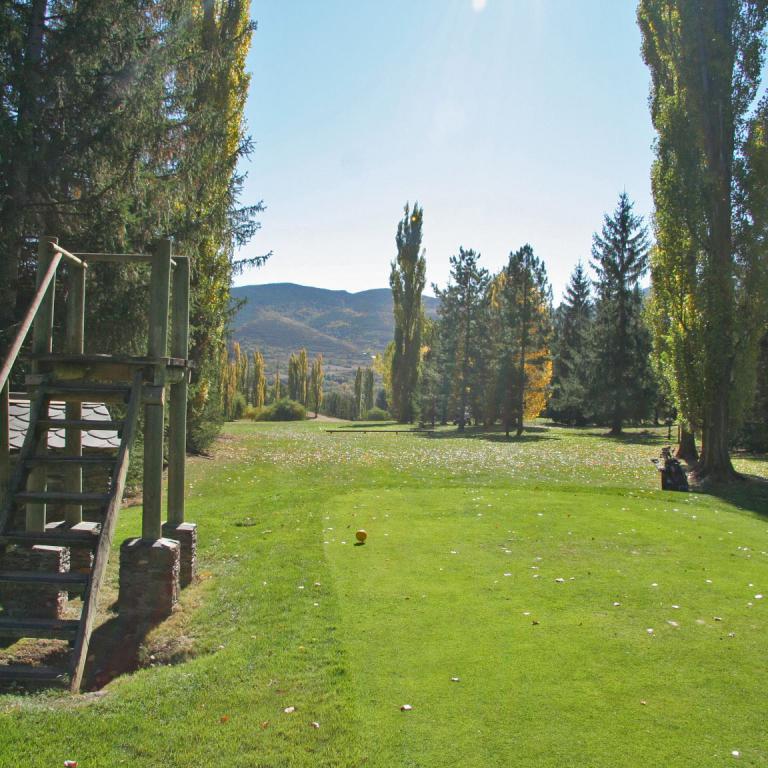 Ein Spielgerät mit Treppensätzen und einem Spielplatz in einer grünen Parklandschaft unter blauem Himmel.