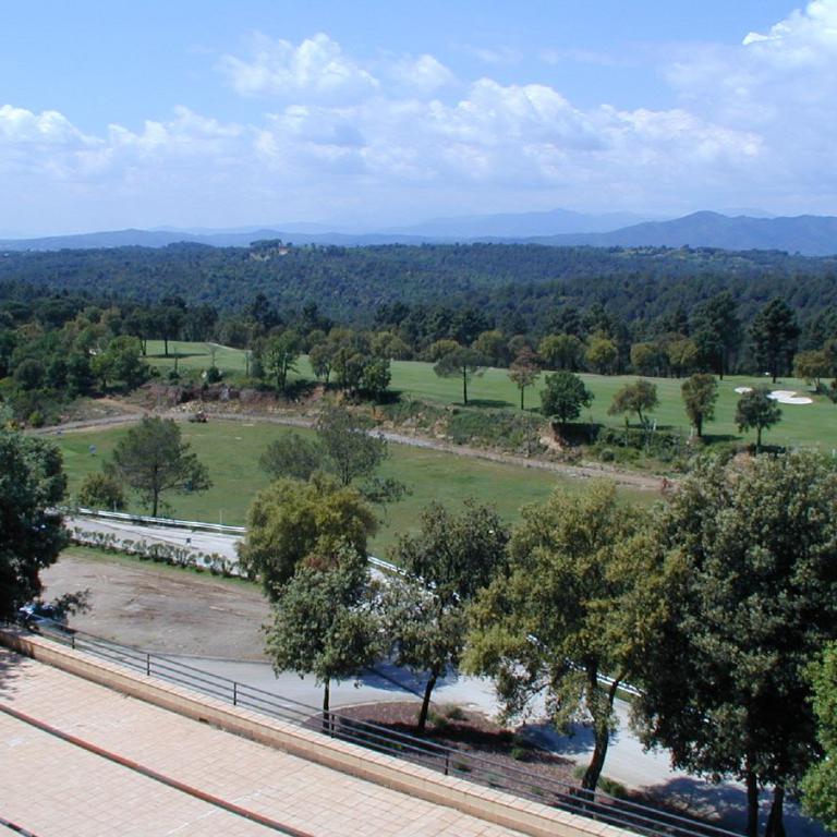 Panoramablick von einer Terrasse über eine weite, grüne Landschaft mit Golfplatz und Wald.