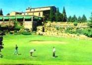 Ein weitläufiger, gepflegter Golfplatz im Vordergrund vor einem großen, historischen Gebäude im Hintergrund.
