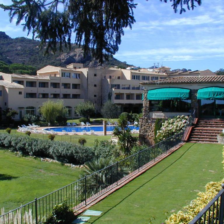 Panoramaansicht eines großen Küstenresorts mit Poolbereich und Blick auf bewaldete Hügel.