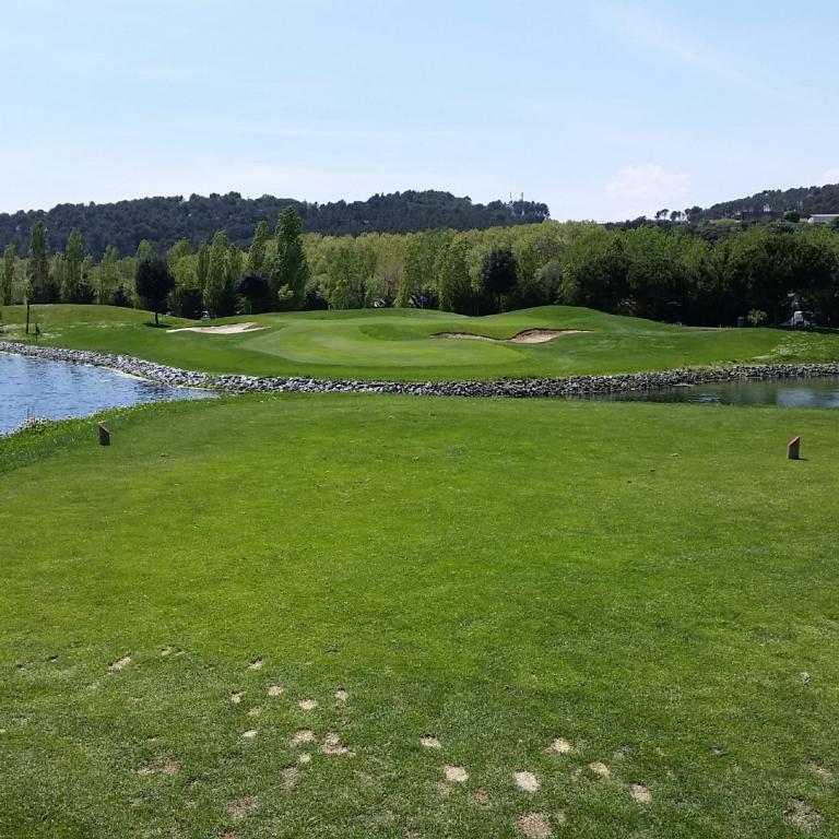Eine weitläufige Golf-Landschaft mit einem großen Wasserteich und einem gepflegten Grün.