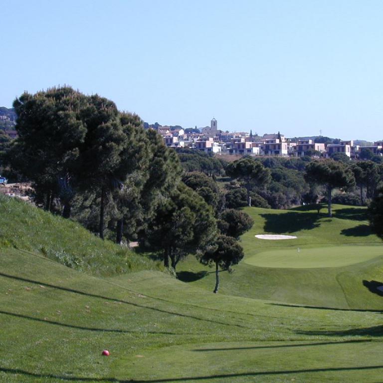 Panoramaaufnahme eines Golfplatzes mit Blick auf eine städtische Siedlung in der Ferne.