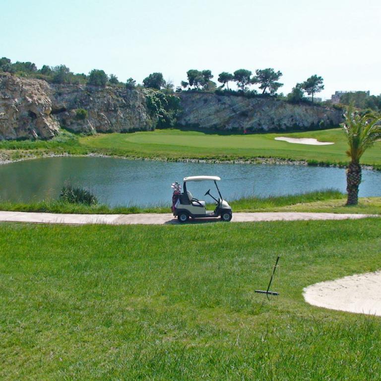 Golfplatz mit Wasserteich und hügeliger Landschaft