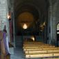 Innenaufnahme eines historischen Kirchenschiffs mit langen Reihen von Holzbänken unter hohen Steinbögen.