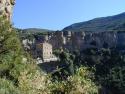 Ein dramatischer Blick auf einen tiefen Canyon mit steilen Felswänden, an deren Rand historische Gebäude zu erkennen sind und die von dichter Vegetati