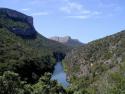 Ein tief eingeschnittener Canyon mit fließendem Fluss, flankiert von steilen, bewaldeten Klippen.