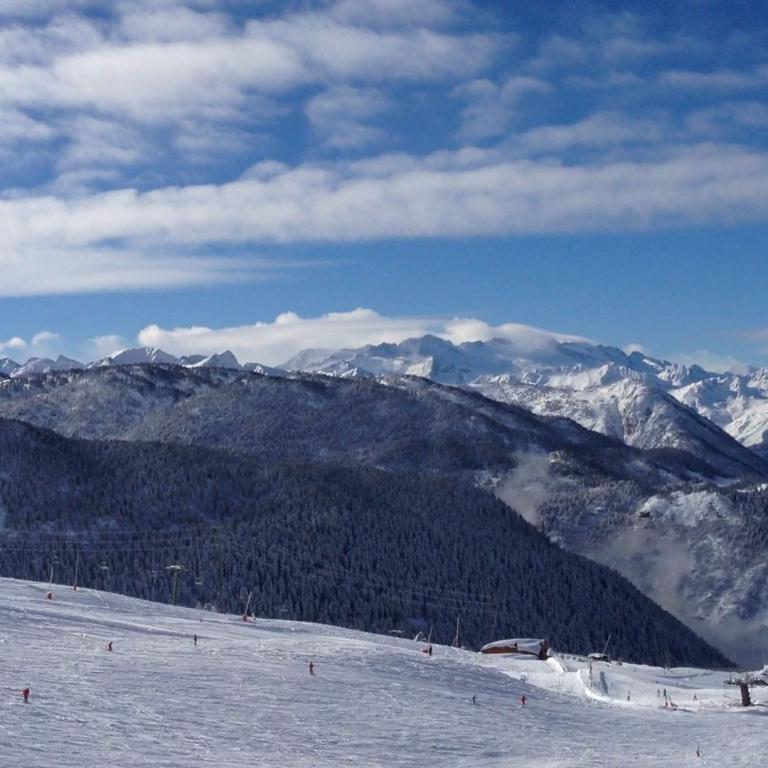 Panoramaansicht schneebedeckter Bergketten mit einem Skihang im Vordergrund