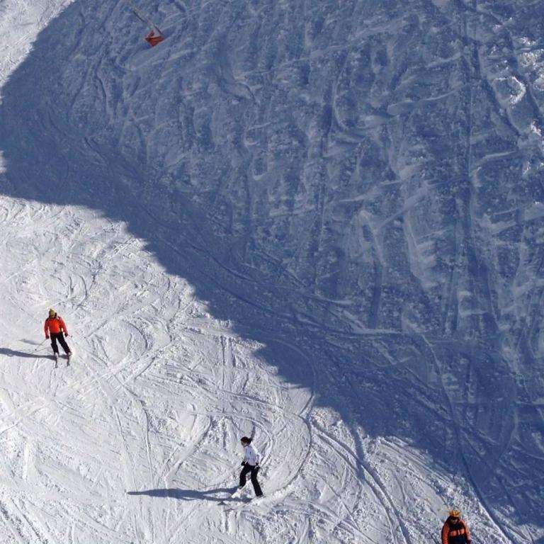 Aerial view of a snowy ski slope with several people skiing.
