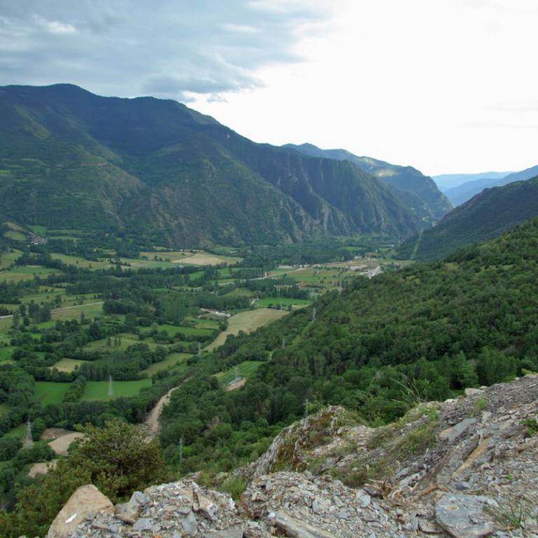 Panoramablick auf ein tief eingeschnittenes, grünes Tal zwischen steilen, bewaldeten Berghängen.