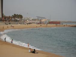 Breite Küstenansicht mit Sandstrand, Meer und Menschen im Hintergrund